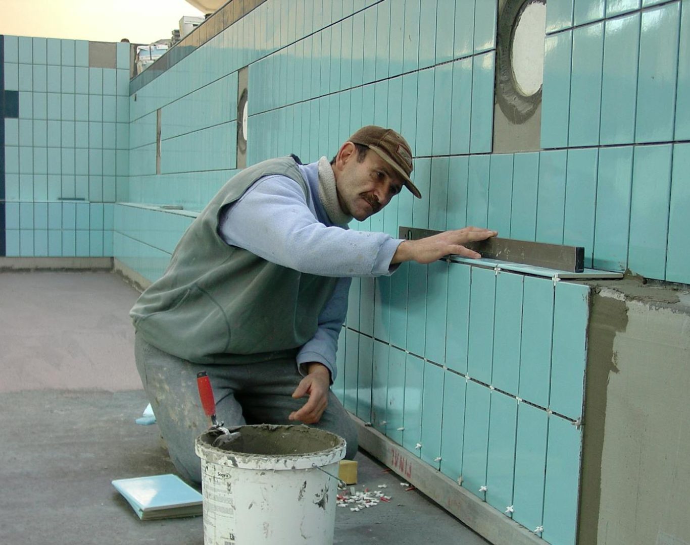 Tiler expertly aligns ceramic tiles on a swimming pool wall. Indoor construction setting in Wrocław.