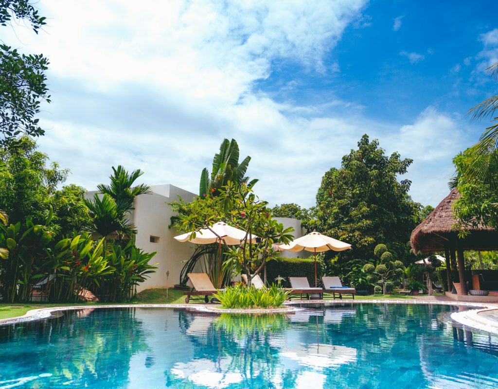 resort with pool, hut, and patio umbrellas