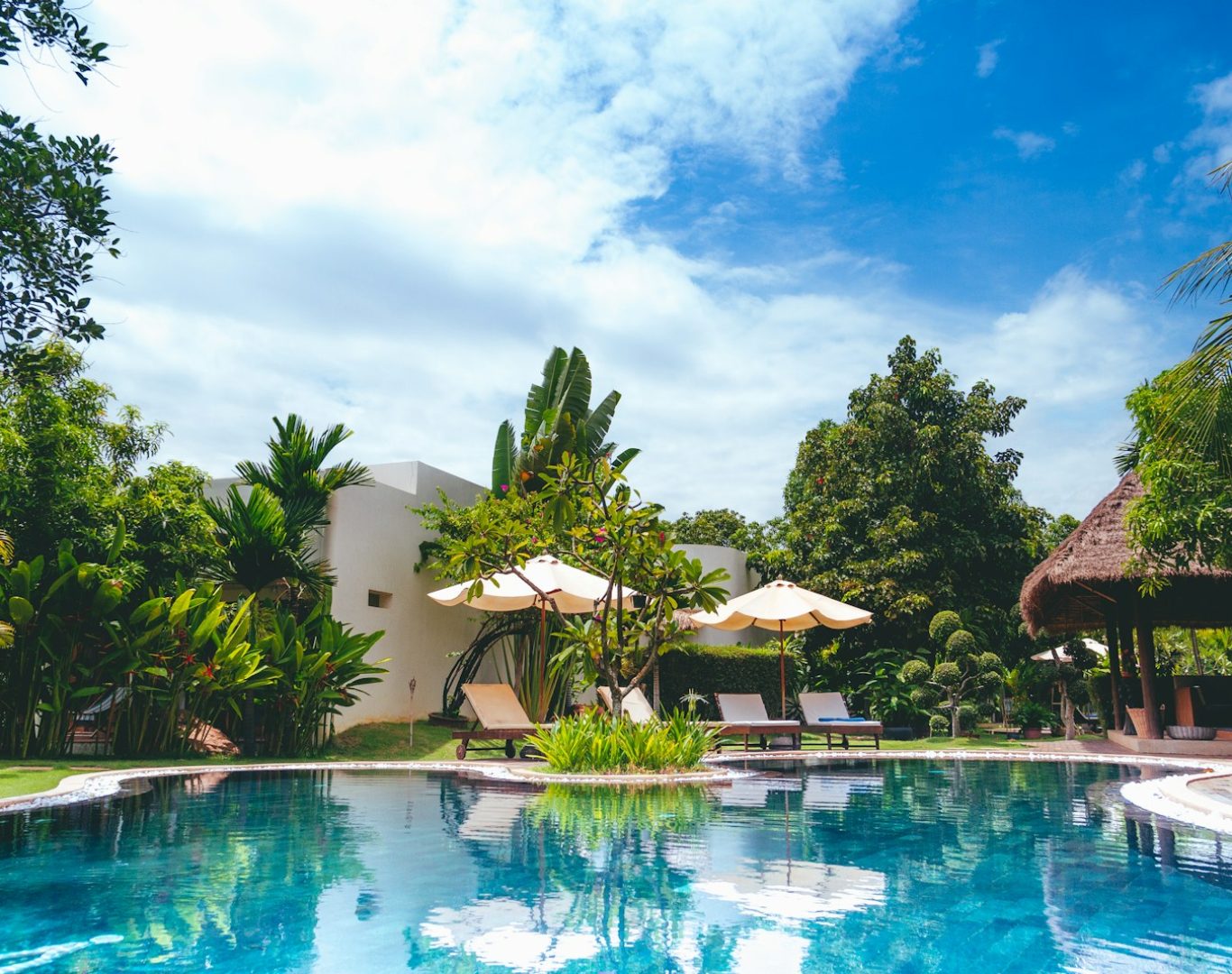resort with pool, hut, and patio umbrellas
